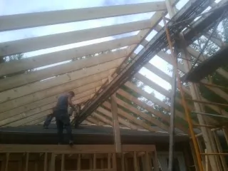 Rafters going up over a new addition with a worker on the wall in West Union